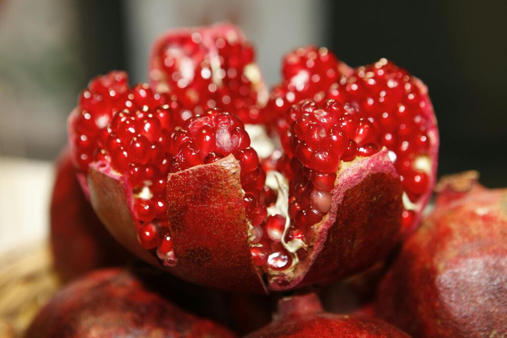 Detailed macro shot of a fresh, vibrant pomegranate exposing its juicy seeds.